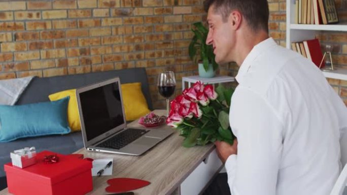 白人男子使用笔记本电脑拿着一束鲜花和吹吻进行视频通话