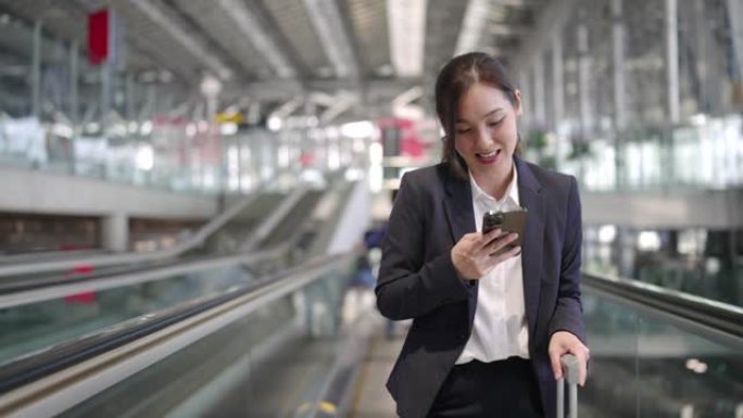 亚洲女商人在机场自动扶梯上使用电话