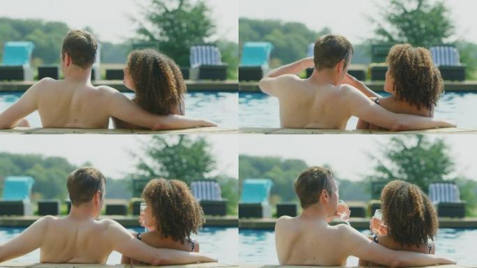 暑假成熟夫妇在室外游泳池喝一杯香槟的后视图 -- 慢动作拍摄