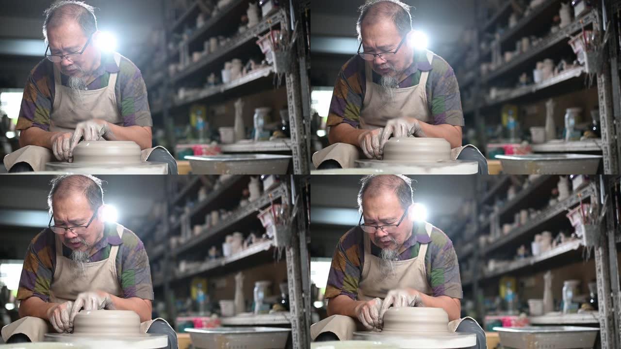 亚洲中国高级陶土艺术家在他的工作室里工作，用旋转的陶轮