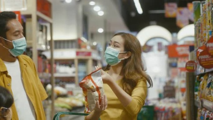 亚洲家庭戴着口罩，在超市买食物。