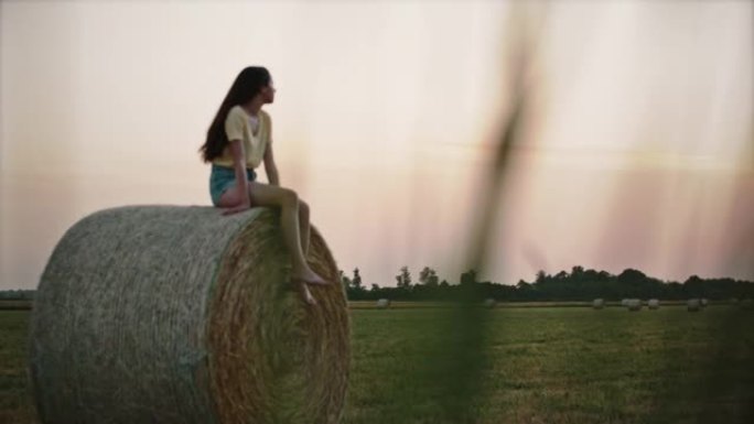 SLO MO年轻女子在一捆干草上放松