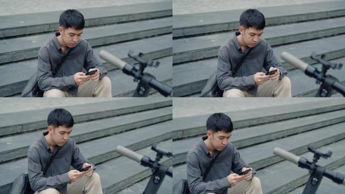 亚洲男子租用电动滑板车使用手机app。
