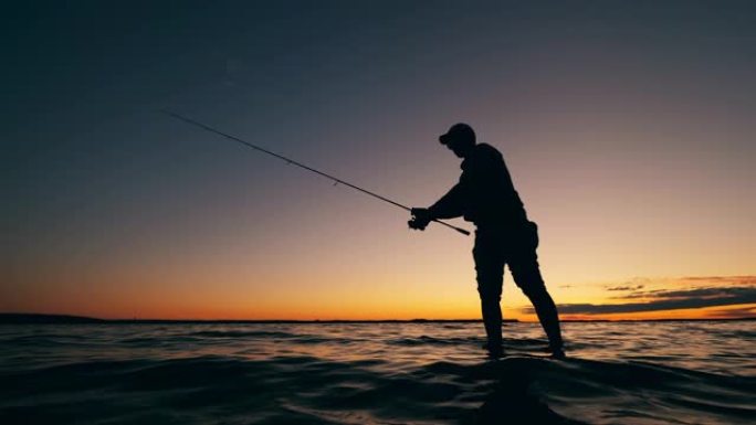 一名男子在日落时将钓鱼竿扔进水中