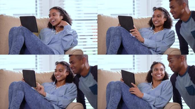 女人在家里使用平板电脑，被打断，对伴侣微笑