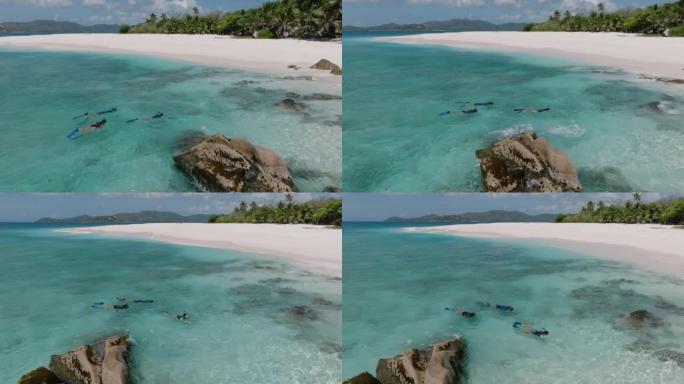 三个人在热带岛屿上浮潜的空中平移视图