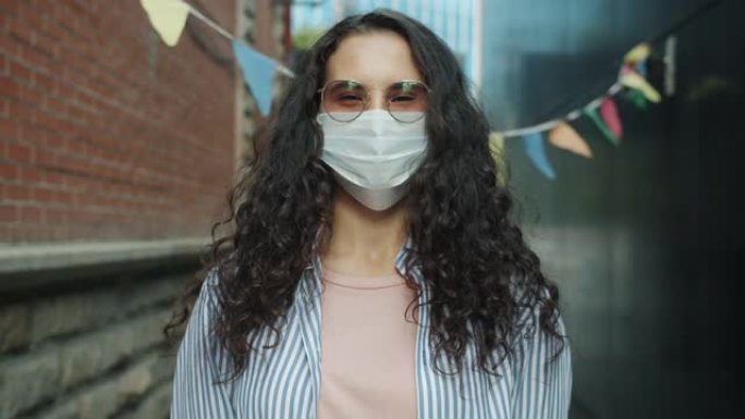 戴着医用口罩的年轻亚洲女士独自站在户外的慢动作肖像