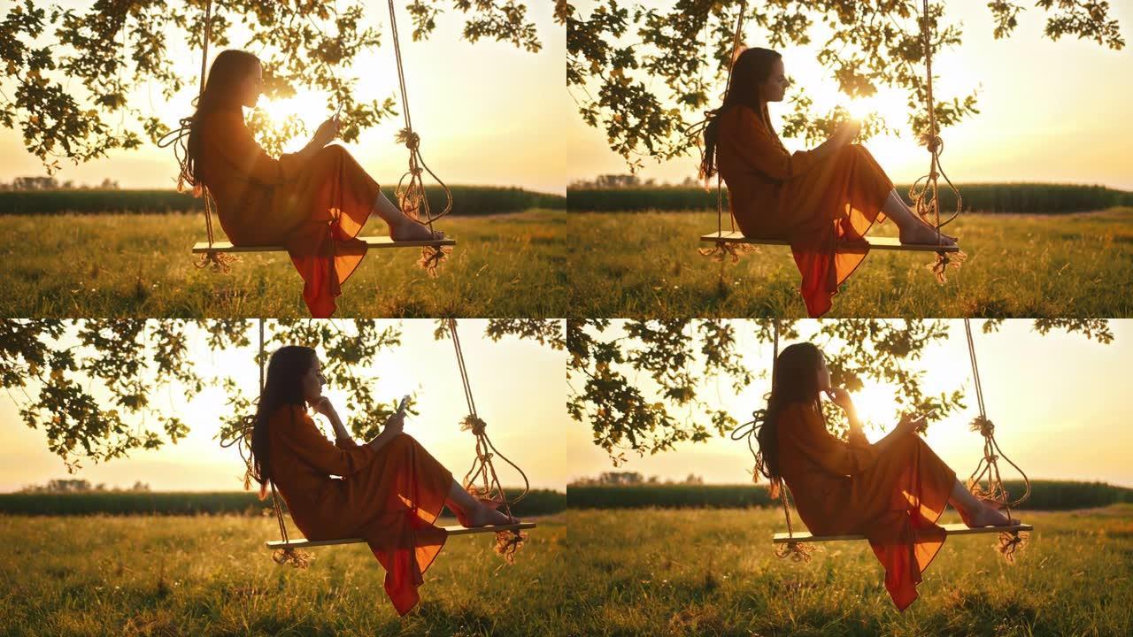 手持镜头，一名穿着红色连衣裙的年轻成年女性摇摆着看着手机，坐在悬挂在大树枝上的绳索秋千上，慢动作