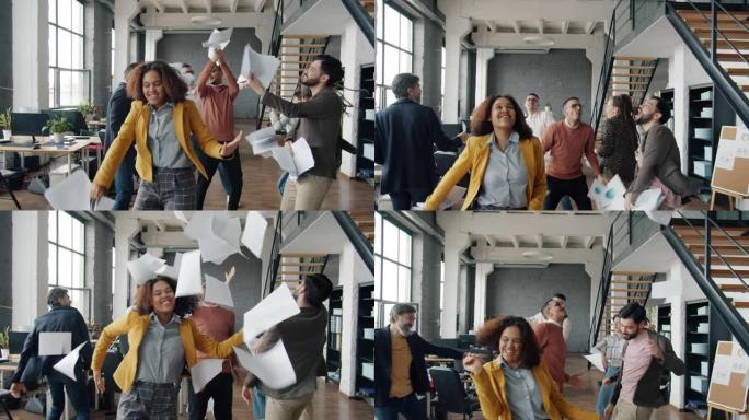 快乐的商人在办公室跳舞的慢动作扔纸玩得开心