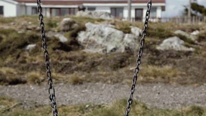 在福克兰群岛 (马尔维纳斯群岛) 斯坦利港的一个公园里，一个空荡荡的生锈链。特写。