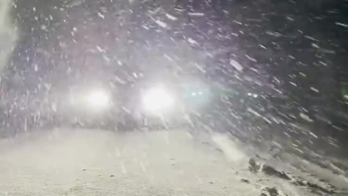 跑车的明亮发光二极管前灯在冬天的夜晚照亮了雪道。