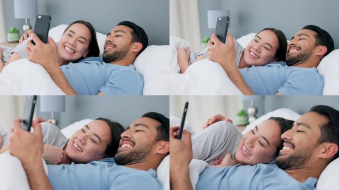 快乐的跨种族夫妇，卧室里有一个亚洲女人和阿拉伯男人的床和电话卷轴。恋爱中的人们在家中放松，在家中查看