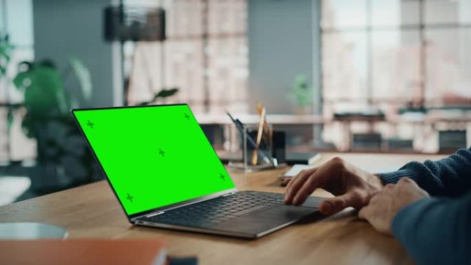 在家庭客厅的带有绿屏模拟显示的笔记本电脑上工作的高加索专家的手关闭。自由职业者在社交网络上通过互联网