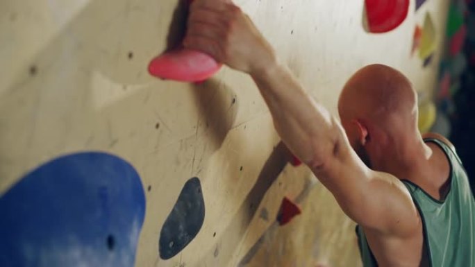 经验丰富的攀岩者在健身房的抱石墙上练习单人攀岩。男子在室内健身设施锻炼，进行极限运动以进行健康的生活