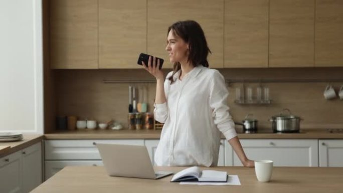 女人站在厨房里用免提电话在手机上交谈
