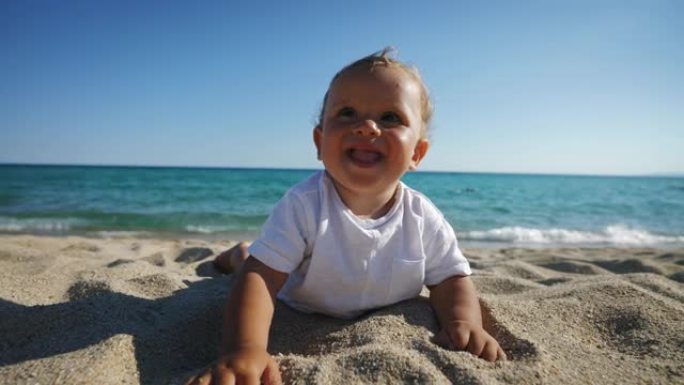 真实的快乐微笑的蹒跚学步的男婴躺在沙滩上