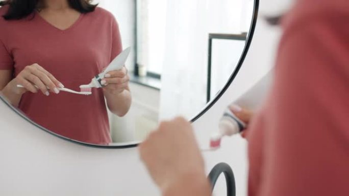 女人的手在浴室的刷子上挤牙膏的特写镜头准备清洁牙齿