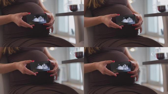 孕妇在家拿着手机的特写带婴儿超声波扫描