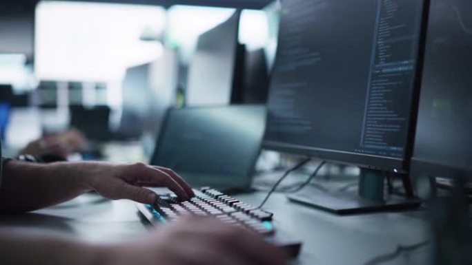 关闭在计算机上工作的软件开发人员，在带有霓虹灯背光的时尚键盘上键入编程代码。在网络安全技术公司工作的