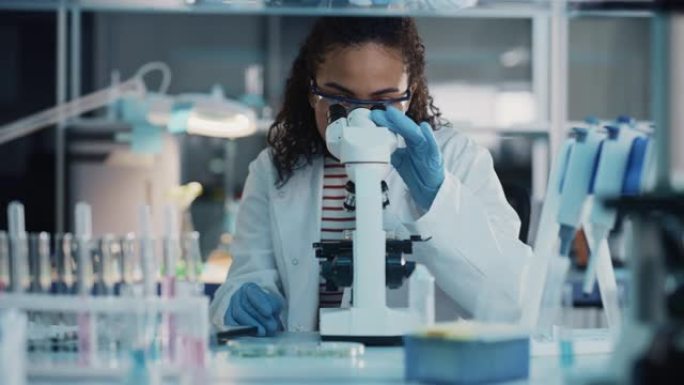 医学科学实验室: 美丽的黑人科学家在显微镜下观察的肖像对测试样品进行分析。雄心勃勃的年轻生物技术专家