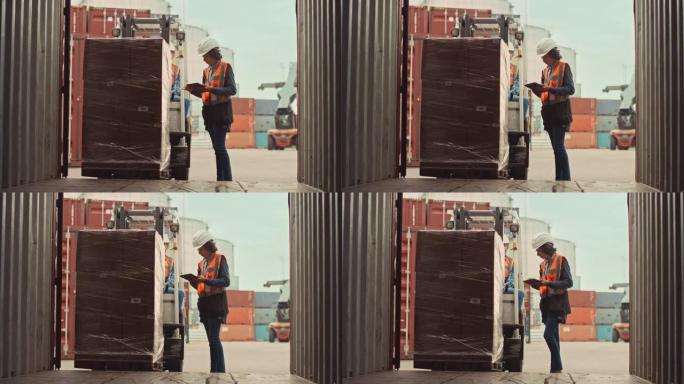 叉车司机在物流港码头装载一个带箱子的完整托盘的运输货物集装箱。拉丁女性工业主管和安全检查员，平板电脑