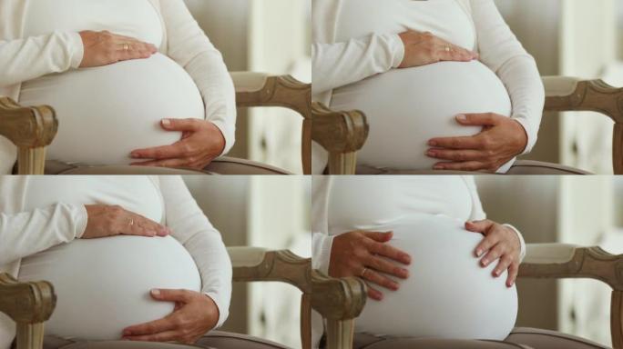 孕妇触摸她坐在扶手椅上的腹部，裁剪镜头