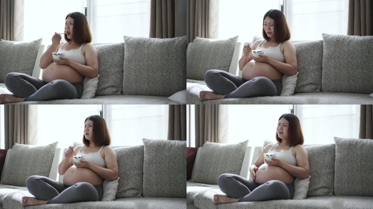 孕妇在家放松，在客厅的沙发上吃早餐