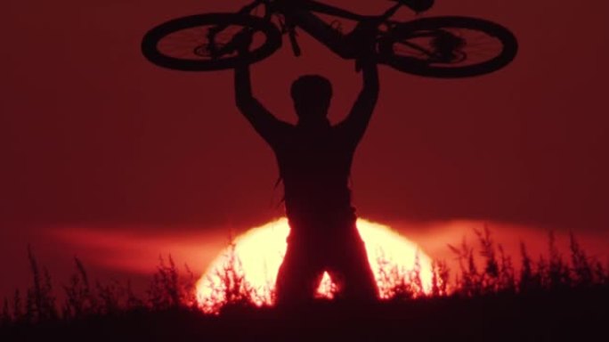 骑自行车的人在日落时举起自行车的剪影