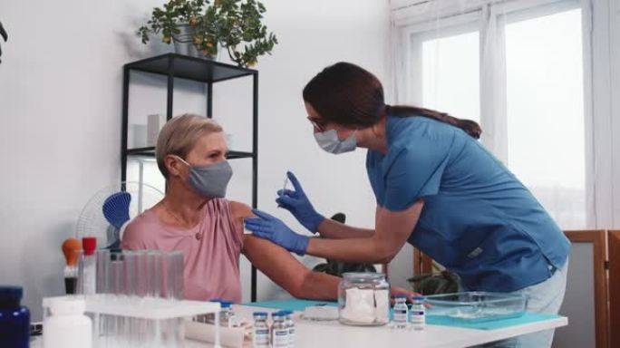 老年人接种疫苗的风险。穿着蓝色磨砂膏的年轻医生在诊所为快乐的老女性患者注射疫苗。