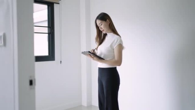 女性室内建筑师在室内分析新家庭室内设计并在数字平板电脑上使用