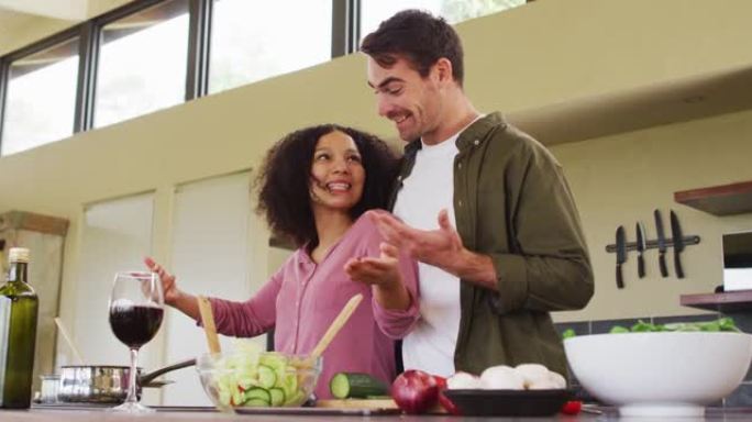 幸福的多元化夫妇在厨房一起准备饭菜，搅拌食物和大笑