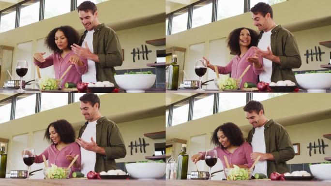 幸福的多元化夫妇在厨房一起准备饭菜，搅拌食物和大笑