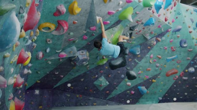男性登山者爬上墙然后落在安全撞击垫上的慢动作