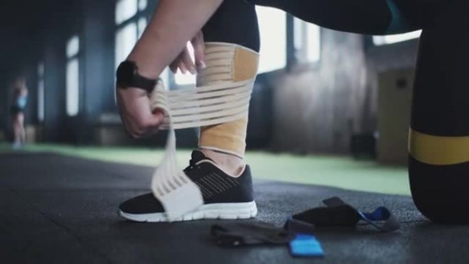 运动医学和技术。特写女运动员在腿上贴上弹性护膝胶带，为健身房锻炼做准备。