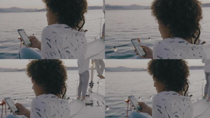 SLO MO年轻女子在帆船甲板上使用智能手机