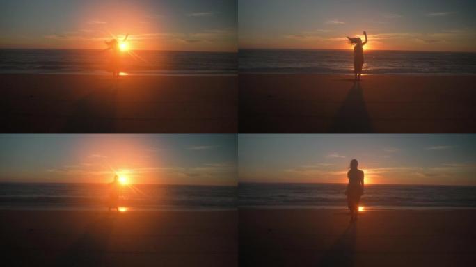 WS日落时在海滩上跳舞的年轻女子的剪影