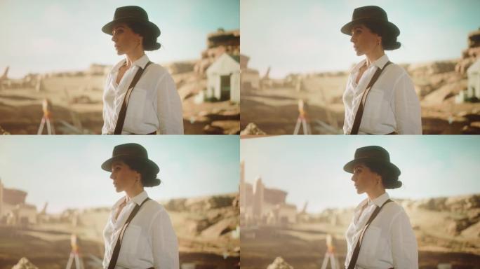 美丽的女冒险家戴着帽子摆姿势看着相机的肖像。时尚的伟大考古学家站在古代文明的背景下，化石遗迹考古遗址