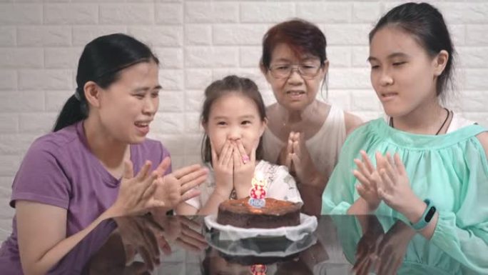 多代家庭正在庆祝小女孩的生日，家庭正在唱生日歌，女孩正在蛋糕上吹蜡烛