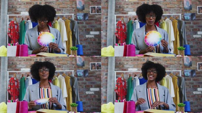 非裔美国女时装设计师展示颜色托盘看着相机和微笑