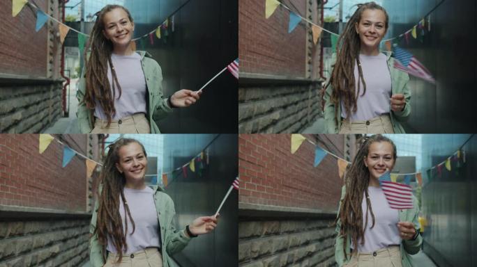 这是一幅可爱的女学生的肖像，她留着长发绺，站在外面挥舞着美国国旗，微笑着看着镜头