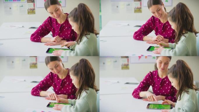 老师和女学生在学校教室里一起使用数字平板电脑