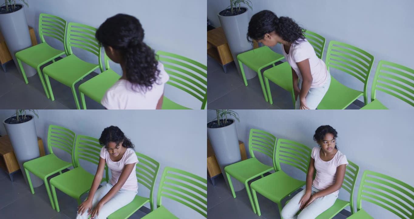 非裔美国女孩坐在医院走廊的椅子上