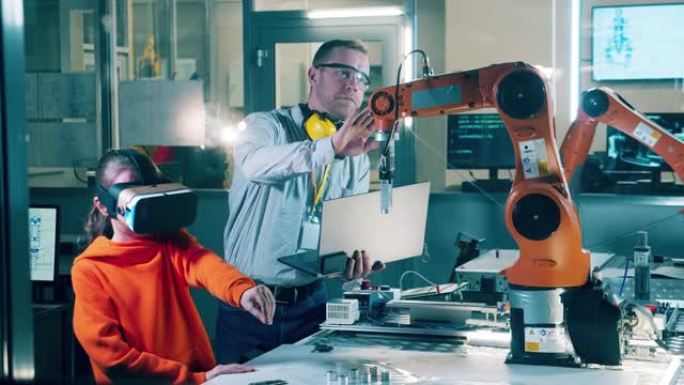 一个戴VR眼镜的女孩和一名工程师正在操作机械臂