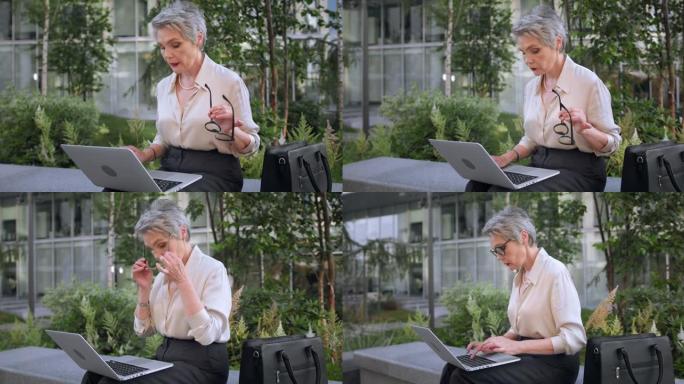 一位才华横溢的白发女作家正在笔记本电脑上创作一本新书，手里转动着眼镜，坐在商务中心前