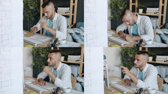有吸引力的家伙的慢动作肖像建筑师绘制施工计划看着电脑屏幕在家里工作