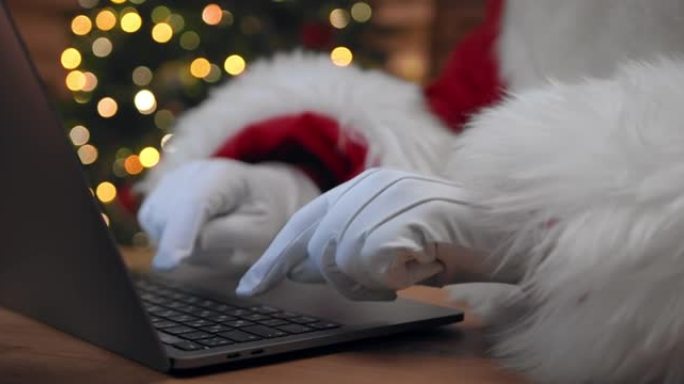 圣诞老人的手的特写视图，在他的笔记本电脑中输入一条消息