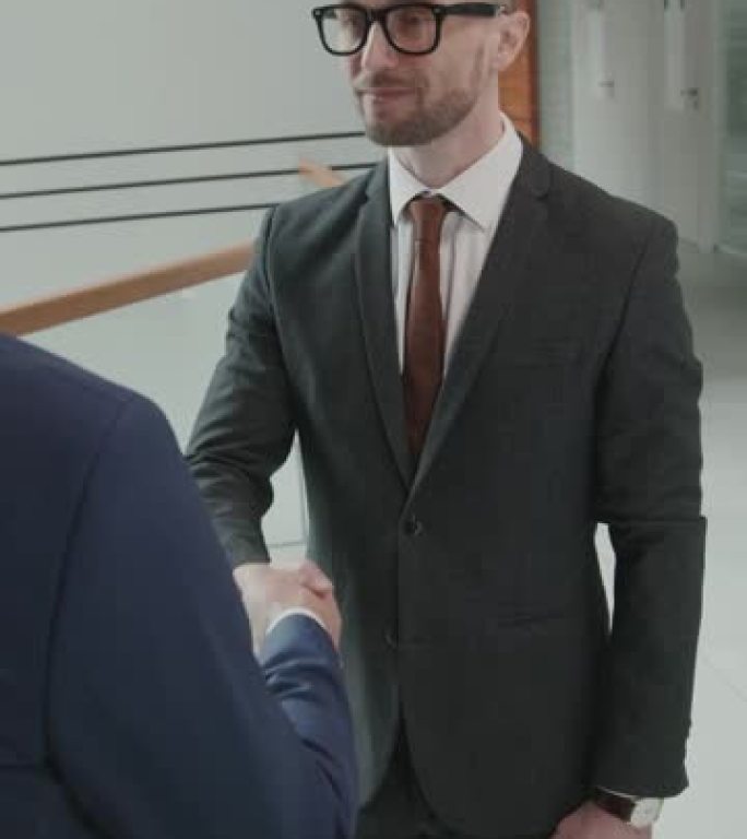 男性律师在办公室与客户握手的垂直镜头