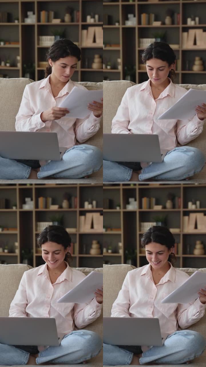 微笑的女人坐在带笔记本电脑的沙发上处理文件