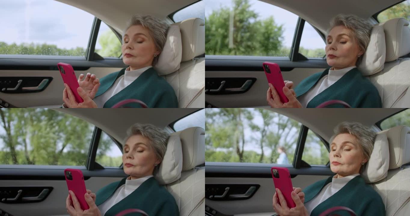 一位发型时尚的中年女商人正在手机里发短信，平静地坐在汽车里，