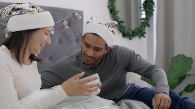 4k视频片段，一对年轻夫妇在圣诞节早上一起在家里的床上交换礼物
